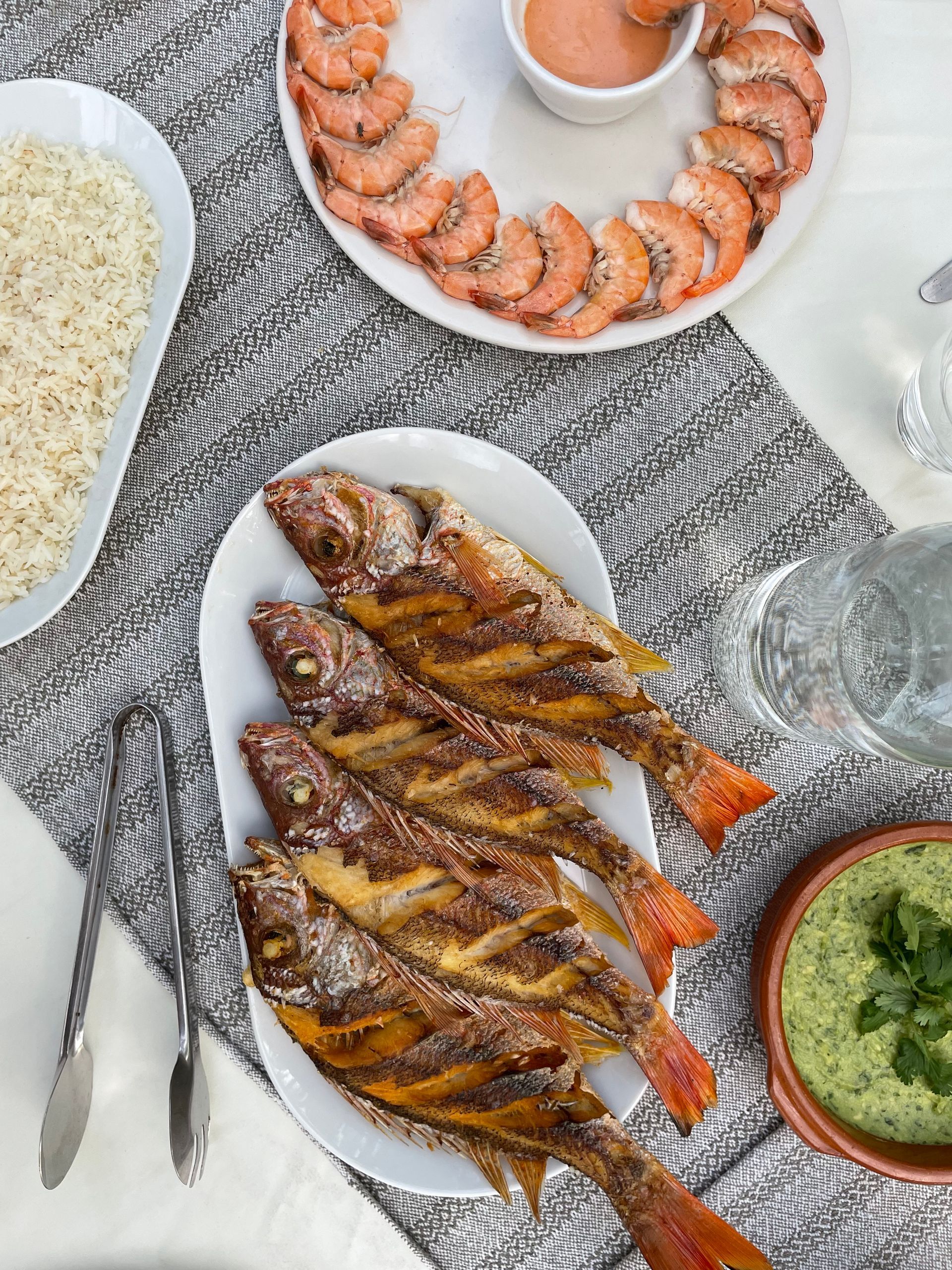 Vista aérea de una comida de mariscos: pescado frito, camarones, arroz y salsas para mojar.