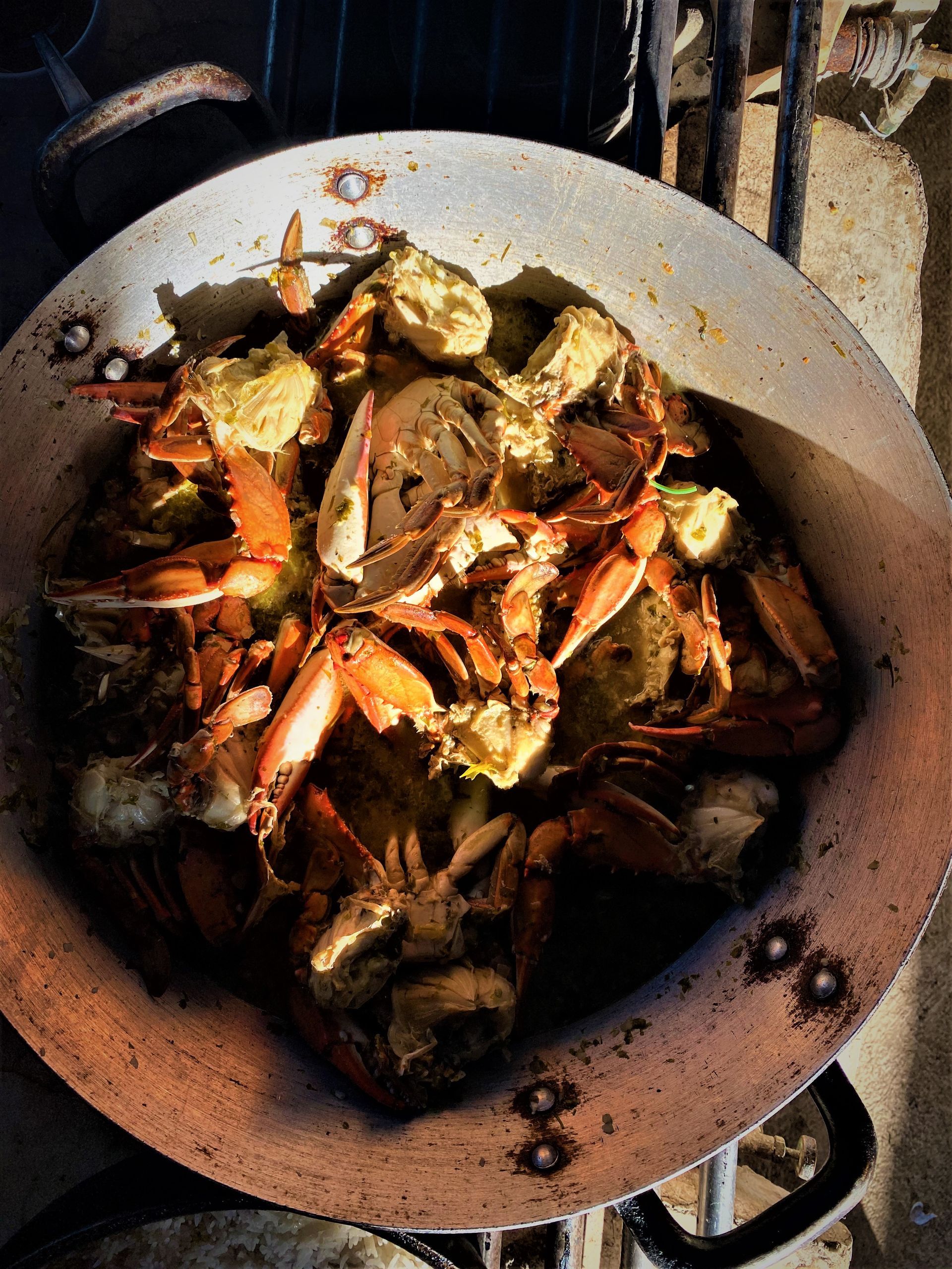 Cangrejos cocinándose en una sartén metálica grande y desgastada.