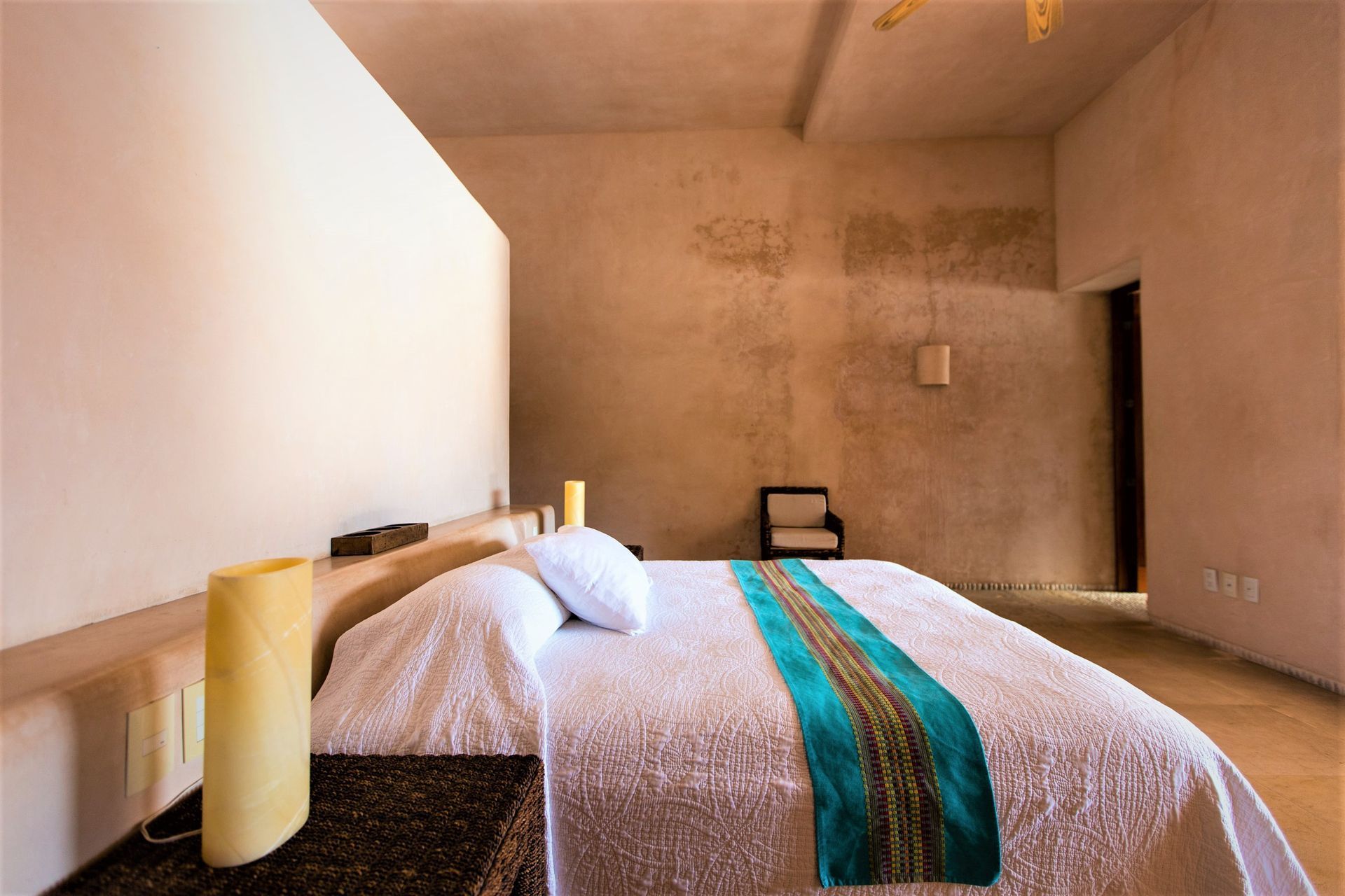 Dormitorio con cama, paredes texturizadas y lámparas de vela.