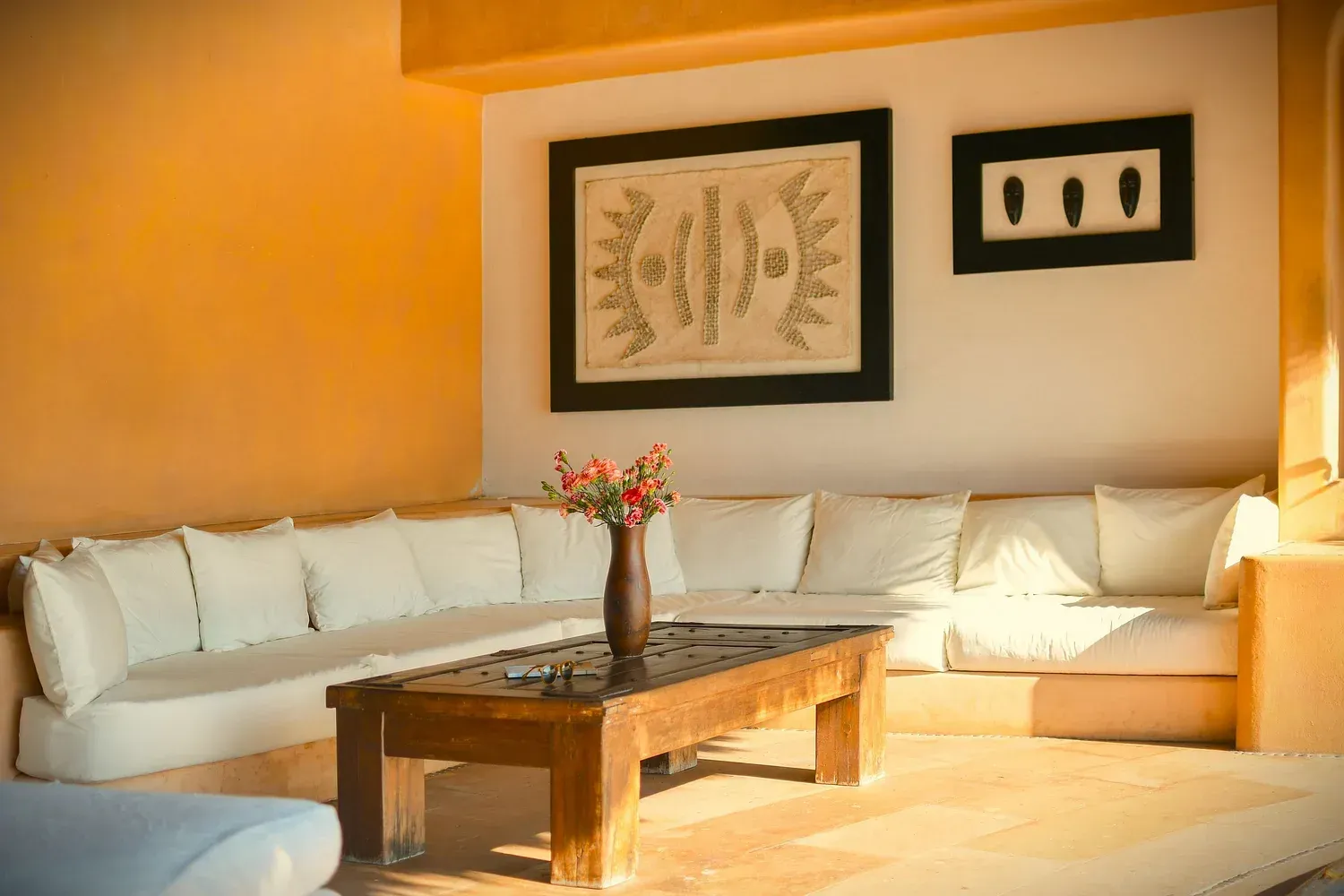 Sala de estar con un sofá seccional blanco, una mesa de centro de madera y arte de pared.