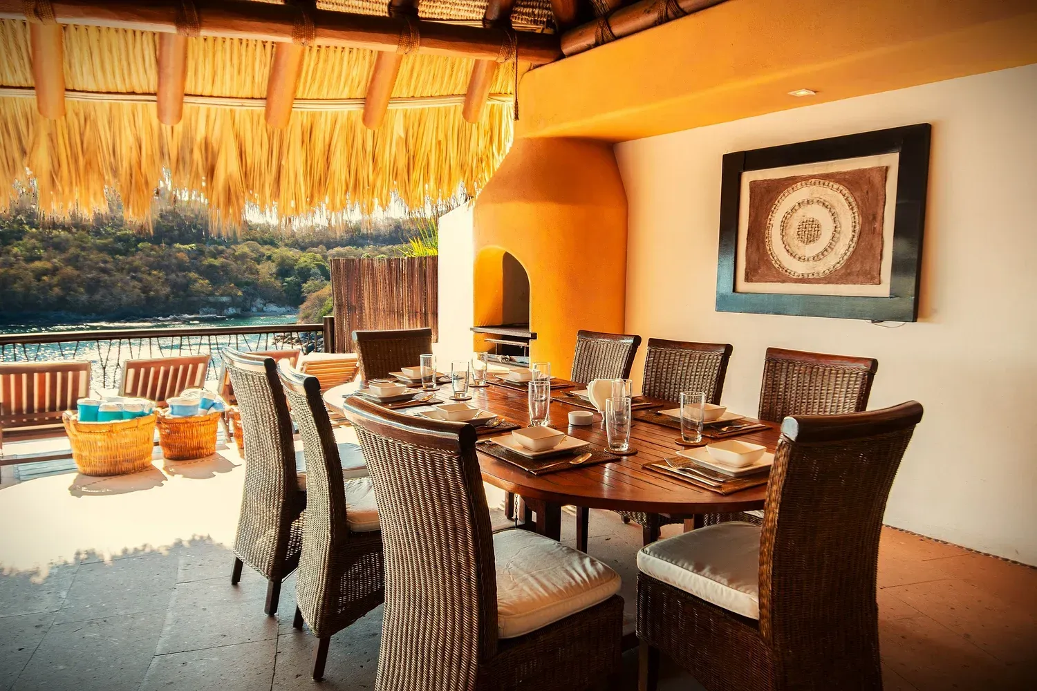 Comedor al aire libre con vista a un cuerpo de agua con una mesa preparada para una comida.