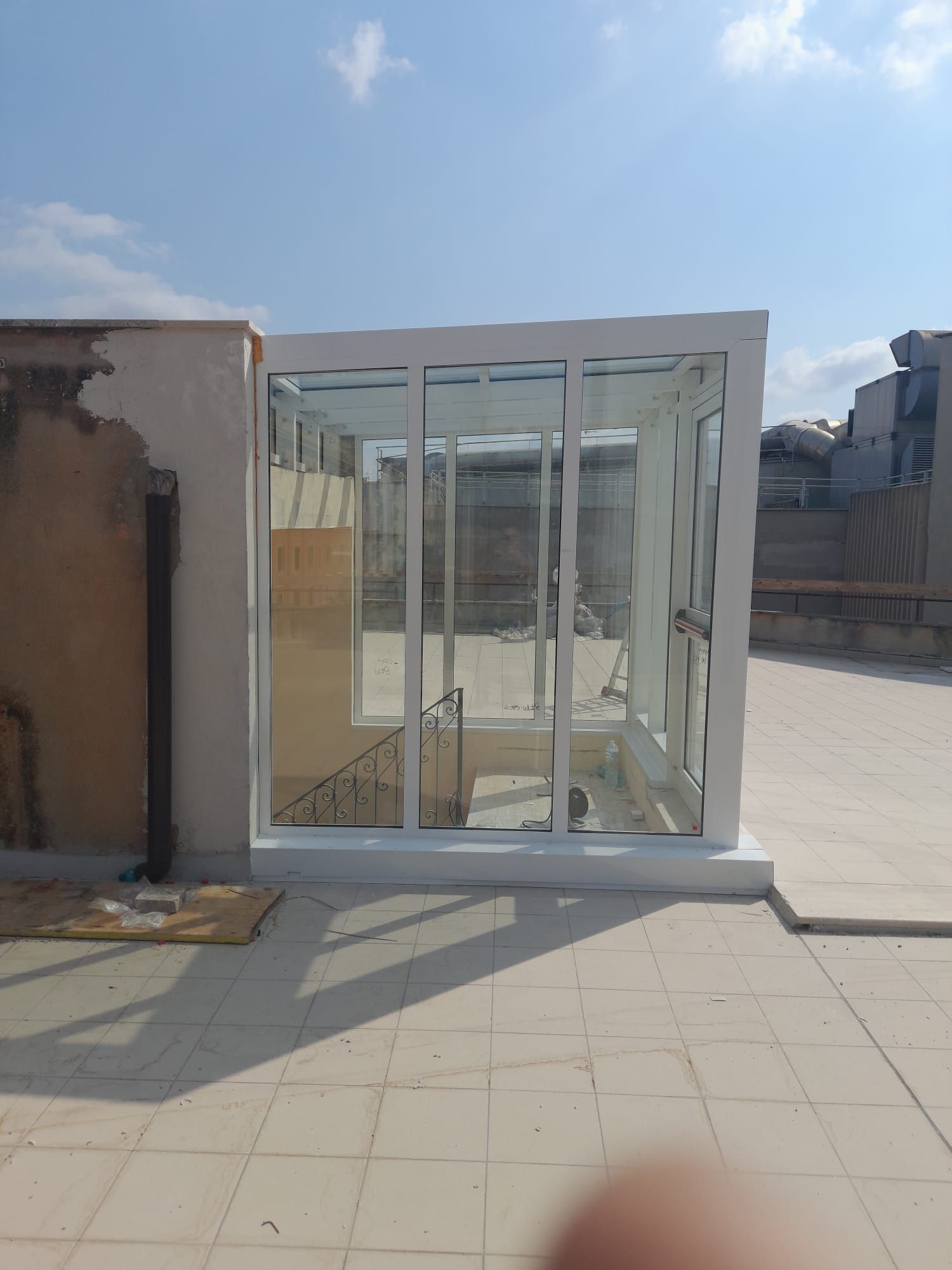 Veranda o struttura in vetro bianca sul tetto, attualmente in costruzione su una terrazza soleggiata.