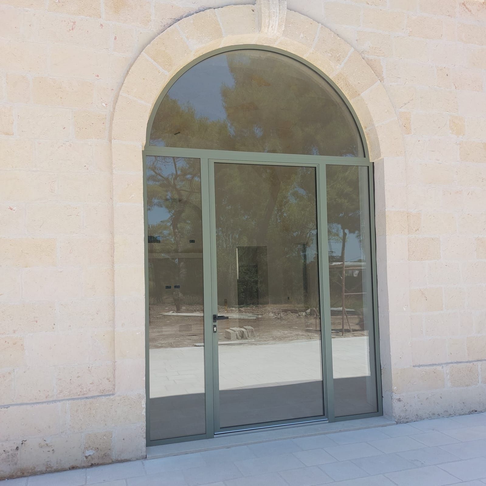 Porta a vetri incastonata in un arco di pietra beige sulla facciata di un edificio.