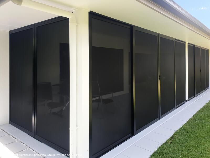 Black framed screen doors along a patio with white trim and a green lawn.