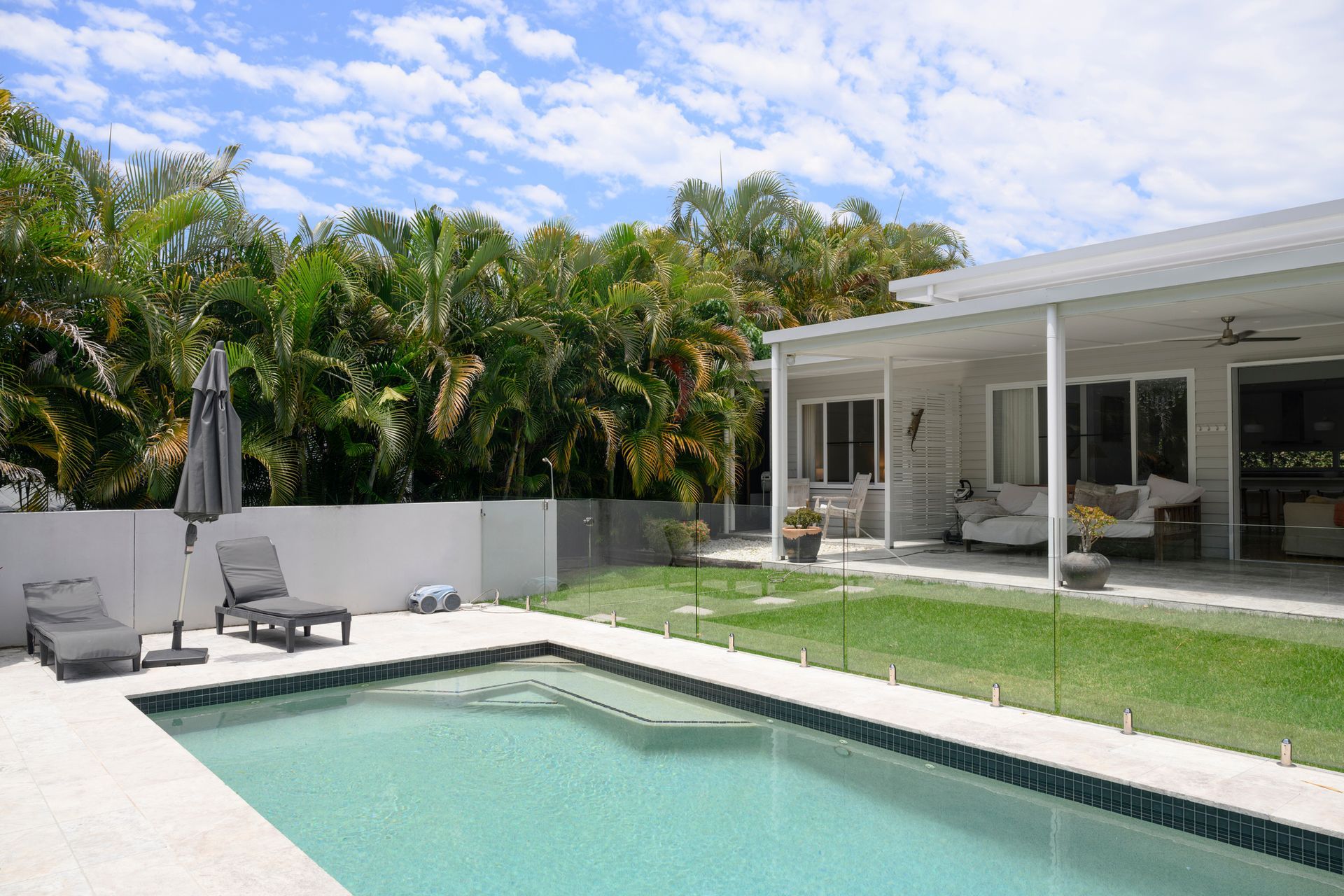 Home with enclosed patio, lawn, poolside lounge chairs and umbrella, and lush palm grove. Home with enclosed patio, lawn, poolside lounge chairs and umbrella, and lush palm grove.