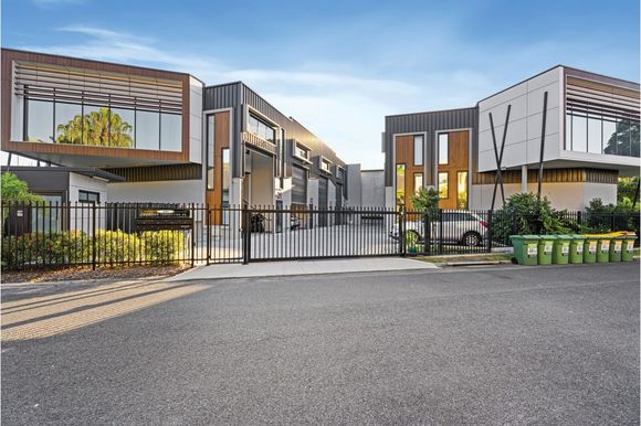 Modern multi-unit buildings with dark exteriors and a gated entrance.