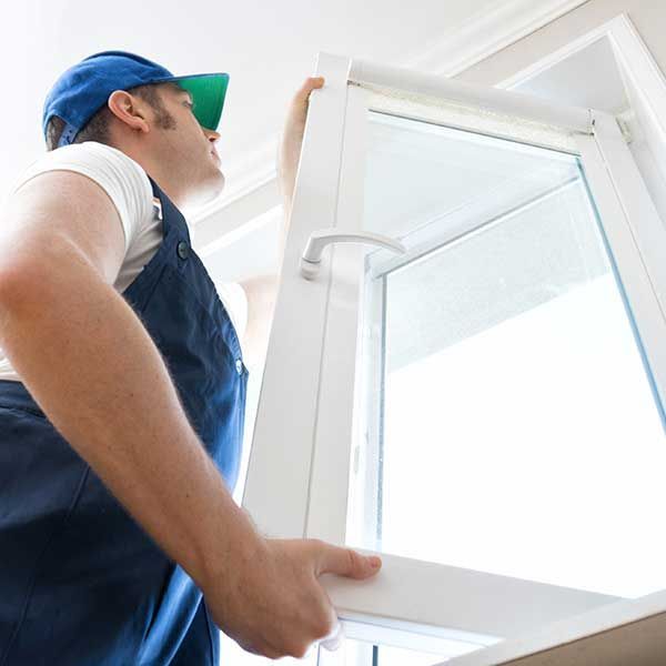 Worker in blue uniform opening a white window indoors