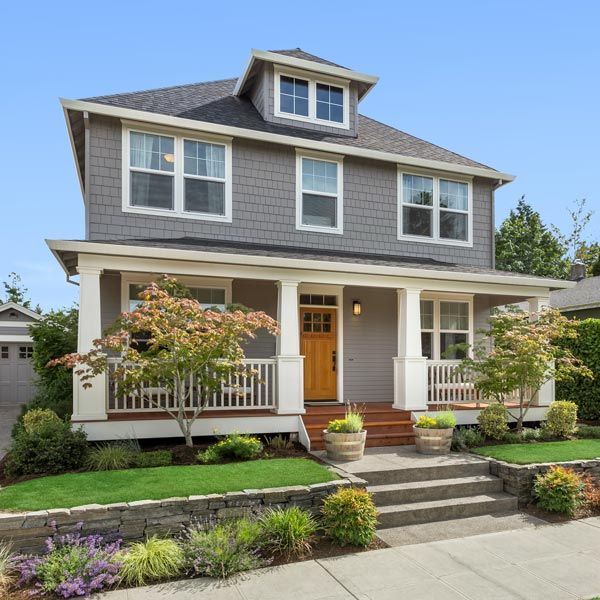 Craftsman-style suburban house with gray siding, white porch, and landscaped front yard