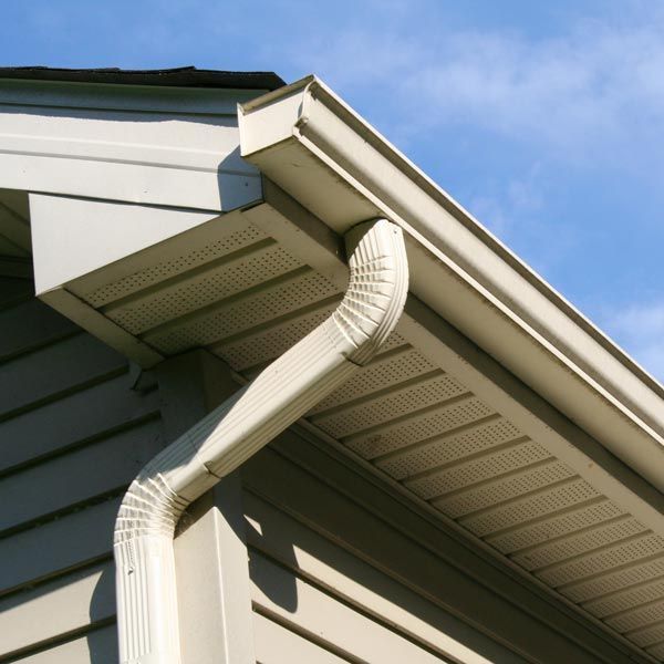 White gutter downspout attached to a house roof under a blue sky