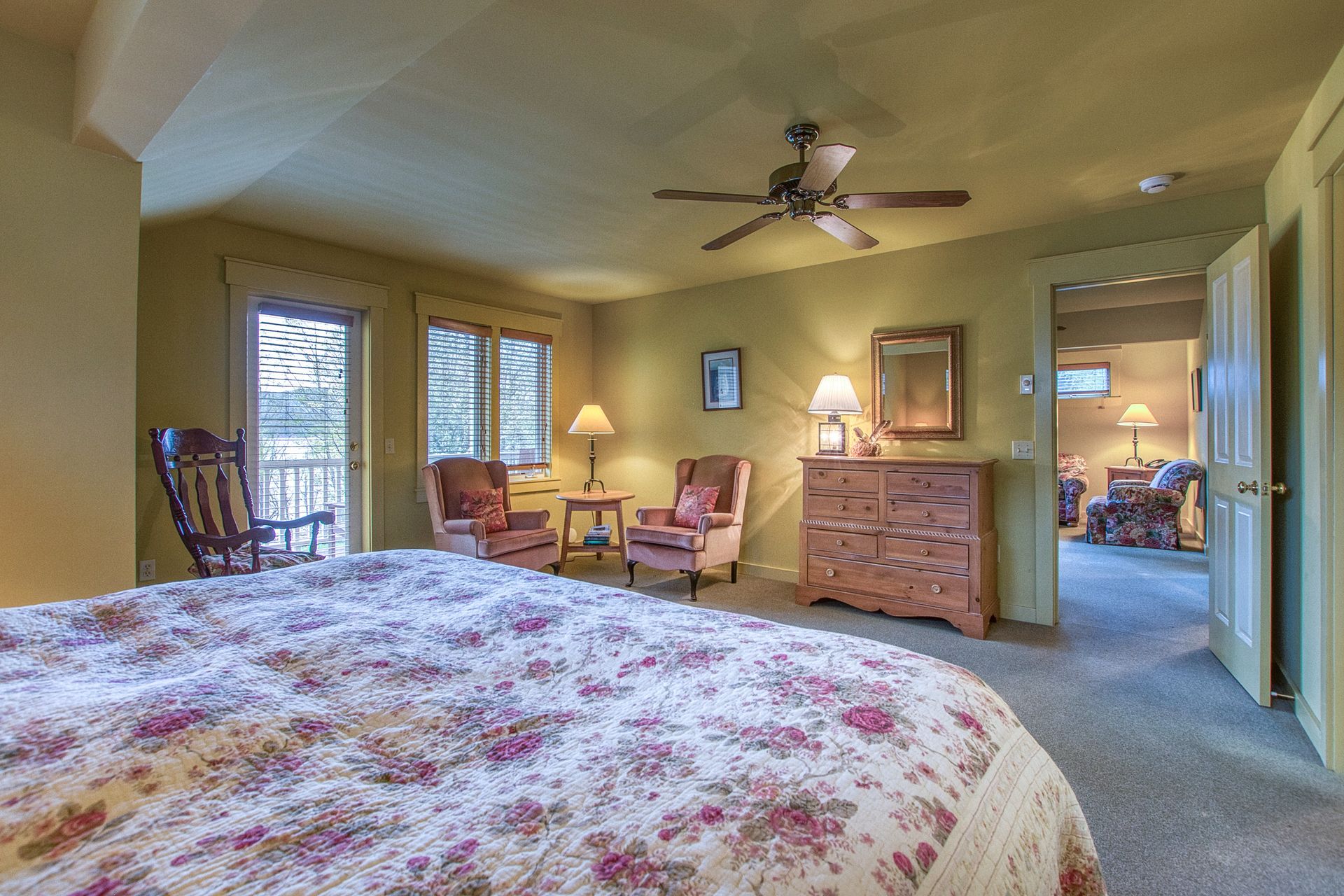 A bedroom with a bed , chair , bench and ceiling fan.