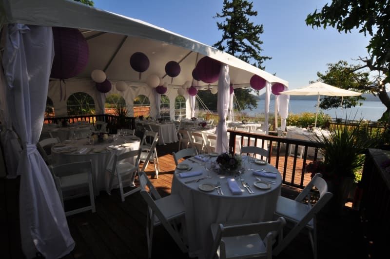 Tables and chairs under a tent with purple decorations