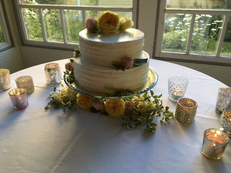 A wedding cake is on a table with candles and flowers.