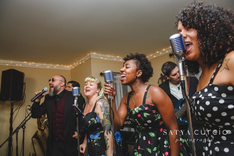 A group of people are singing into microphones in a room.