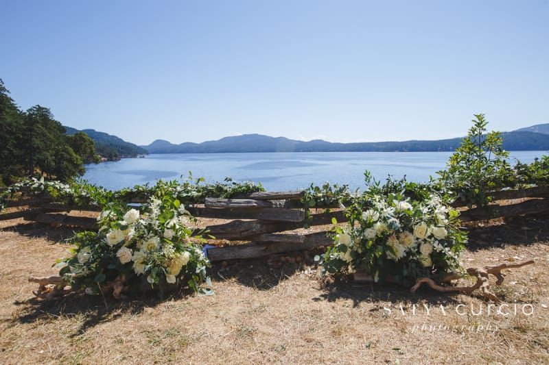 A wooden fence with flowers in front of a lake