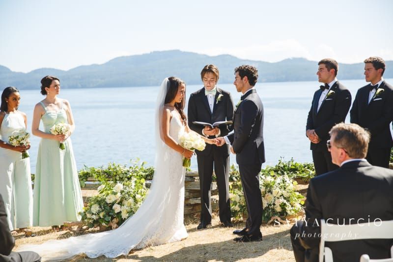 A bride and groom are getting married in front of a lake