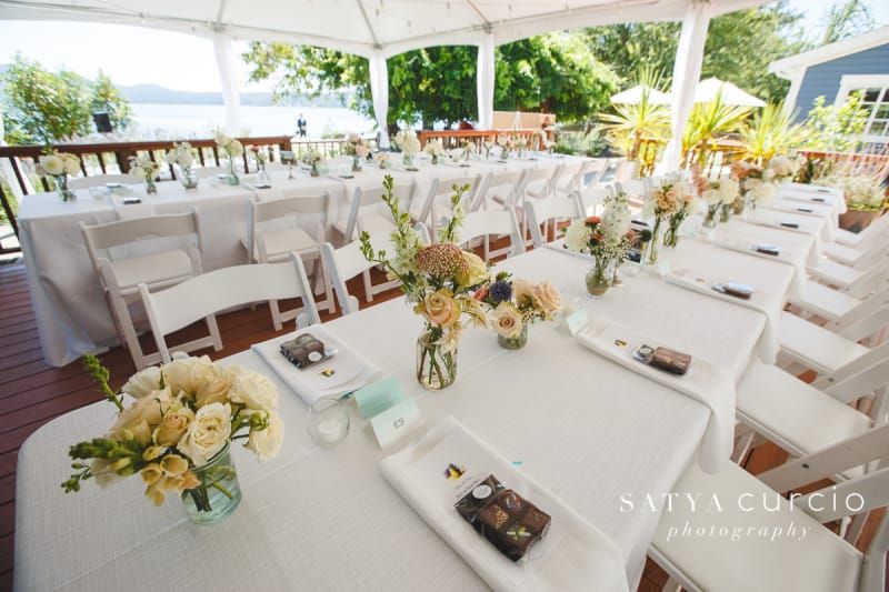 A long table with white chairs and flowers on it