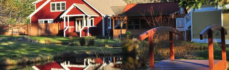 A house with a red roof is next to a bridge over a body of water.