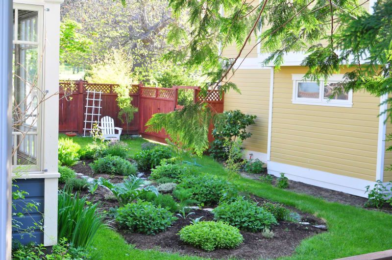 A backyard with a yellow house and a red fence