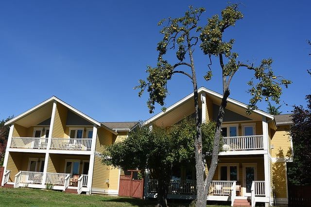 A yellow house with a tree in front of it