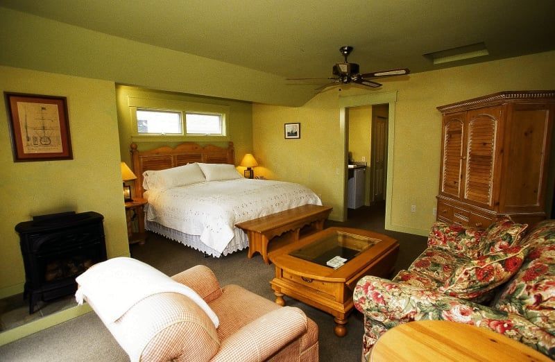 A bedroom with a king size bed a couch a coffee table and a fireplace
