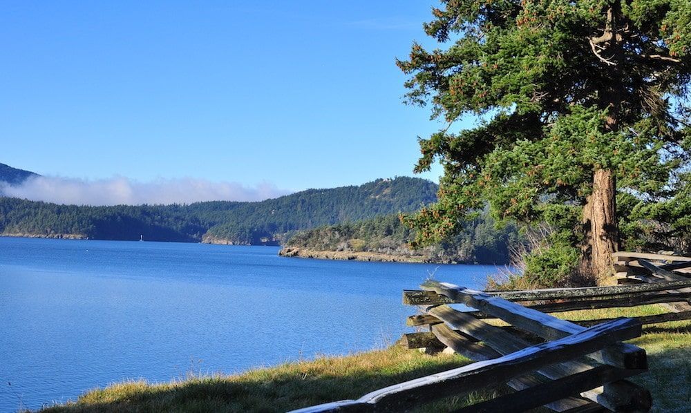 A lake with mountains in the background and a wooden fence in the foreground