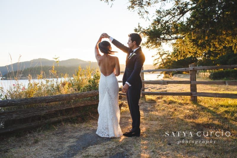 A bride and groom are dancing in front of a wooden fence.