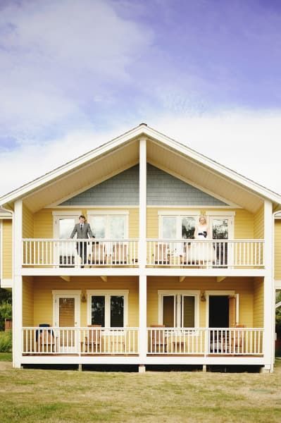 A yellow house with two balconies and a blue sky in the background.