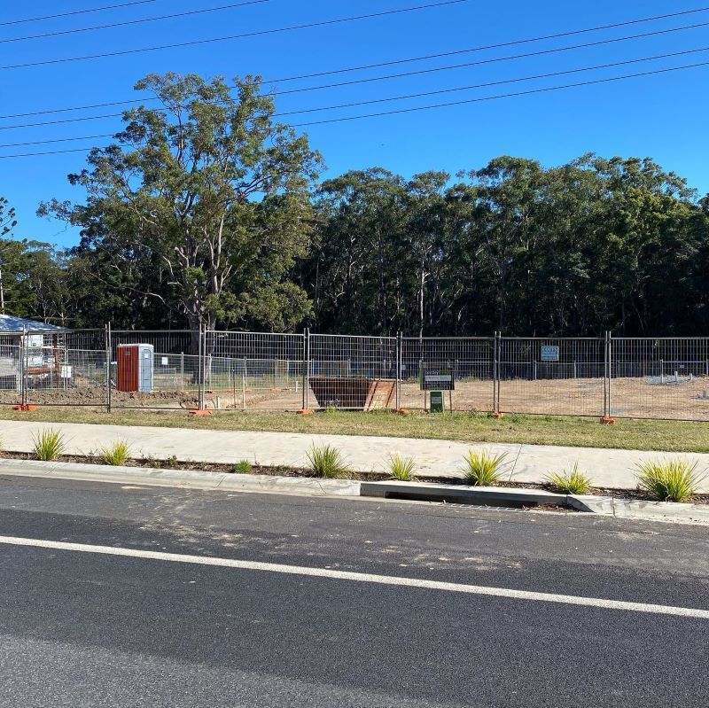 A Road With A Fence And Trees In The Background — Coffs Temporary Fencing Pty Ltd In Moonee Beach, NSW