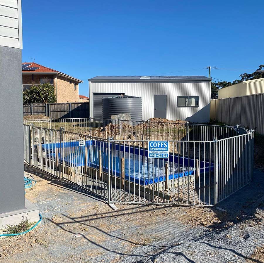 A Fence Around A Swimming Pool With A Sign That Says Coffs — Coffs Temporary Fencing Pty Ltd In Toormina, NSW