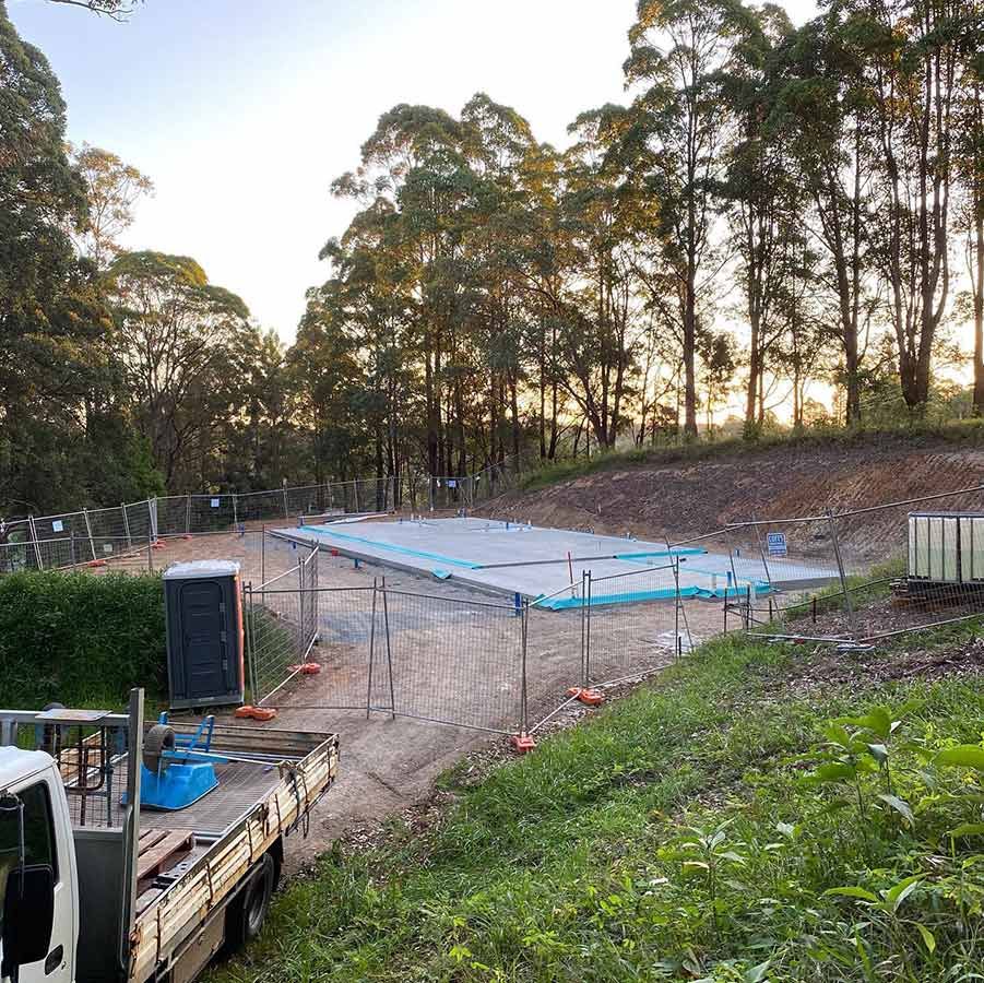 A Truck Is Parked In Front Of A Construction Site Surrounded By Trees — Coffs Temporary Fencing Pty Ltd In Toormina, NSW