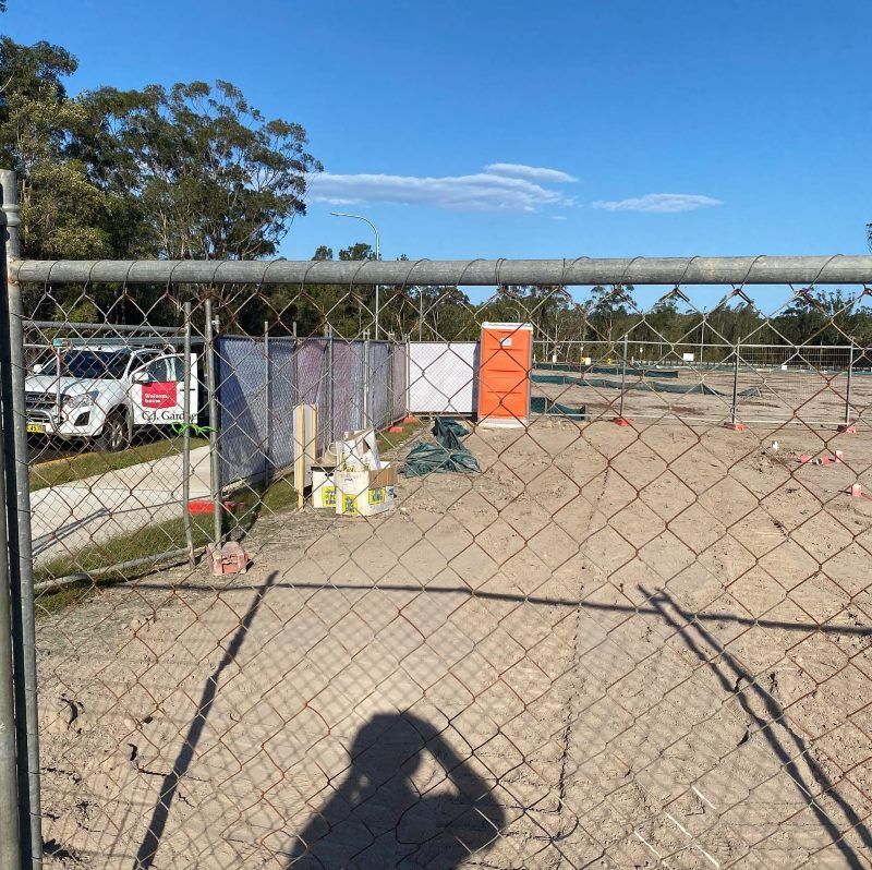 A Chain Link Fence Is Surrounding A Construction Site — Coffs Temporary Fencing Pty Ltd In Macksville, NSW