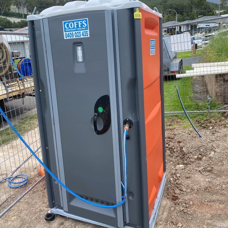 An Orange And Gray Portable Toilet With A Blue Hose Attached To It — Coffs Temporary Fencing Pty Ltd In Dorrigo, NSW