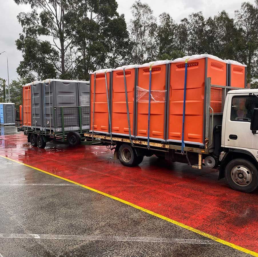 A Truck is towing a bunch of portable toilets — Coffs Temporary Fencing Pty Ltd In Moonee Beach, NSW