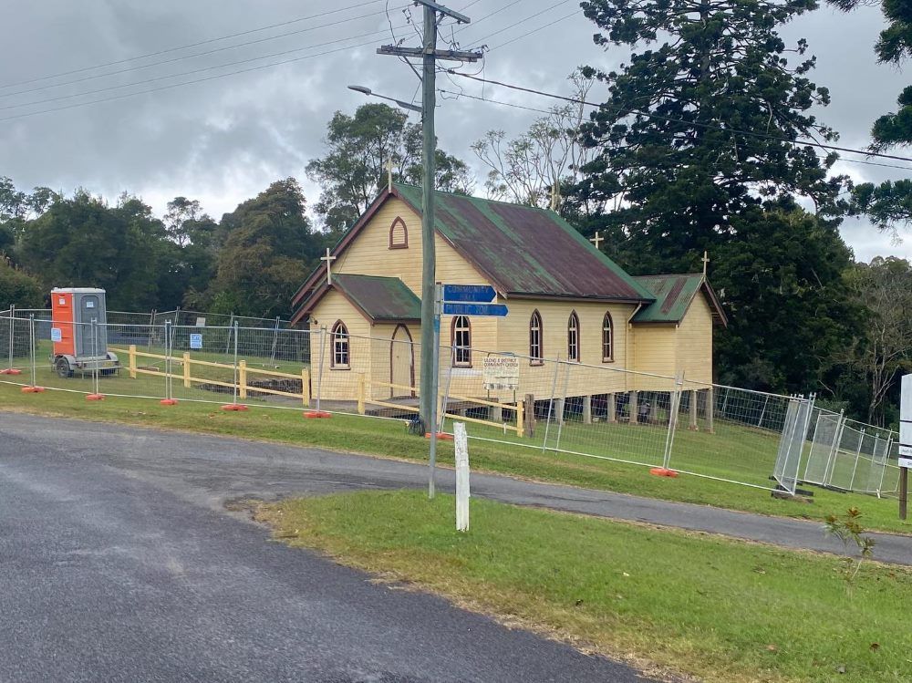 A Small Yellow Building With Fence Around It — Coffs Temporary Fencing Pty Ltd In Woolgoolga, NSW