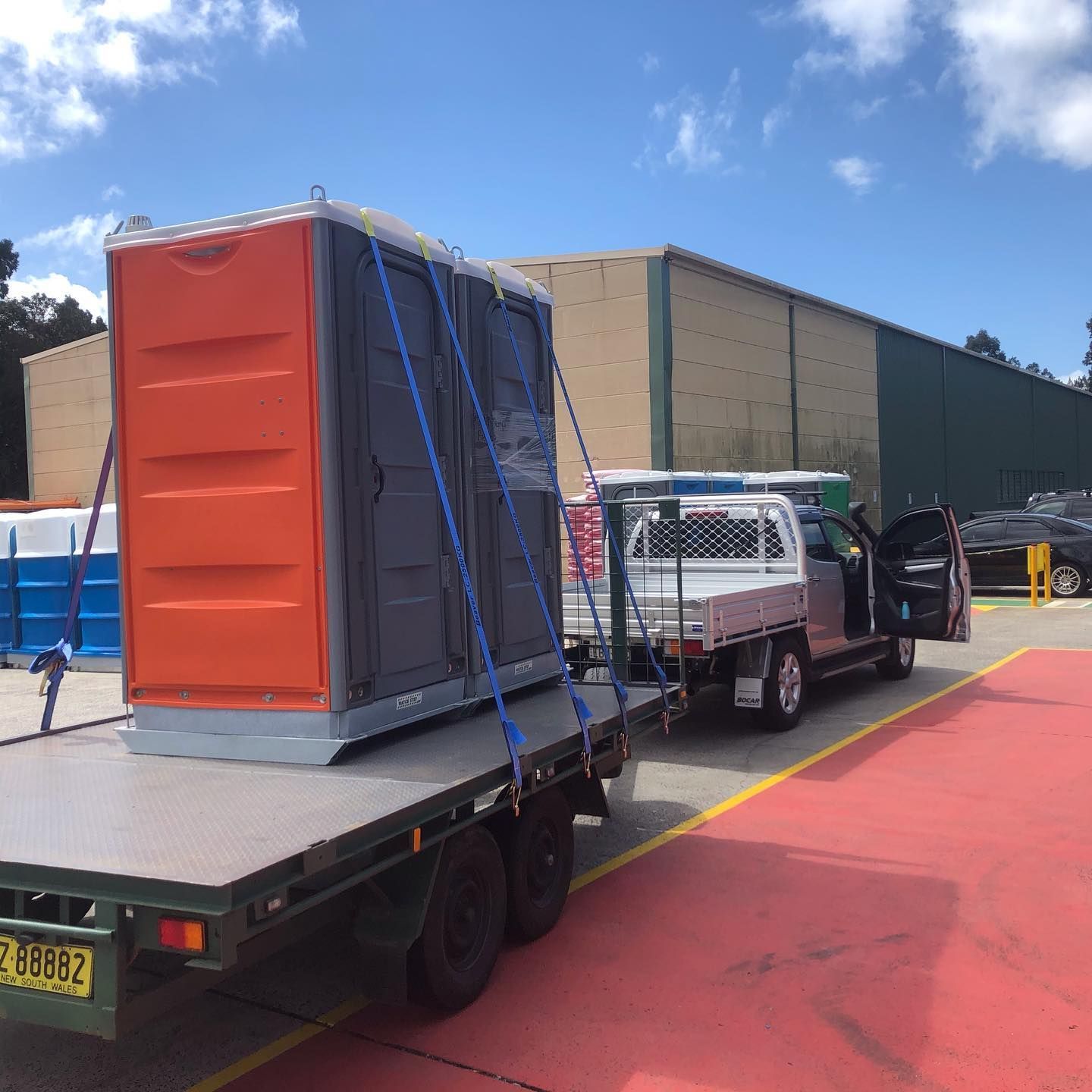 A Truck Is Towing A Portable Toilet On A Flatbed Trailer — Coffs Temporary Fencing Pty Ltd In Moonee Beach, NSW