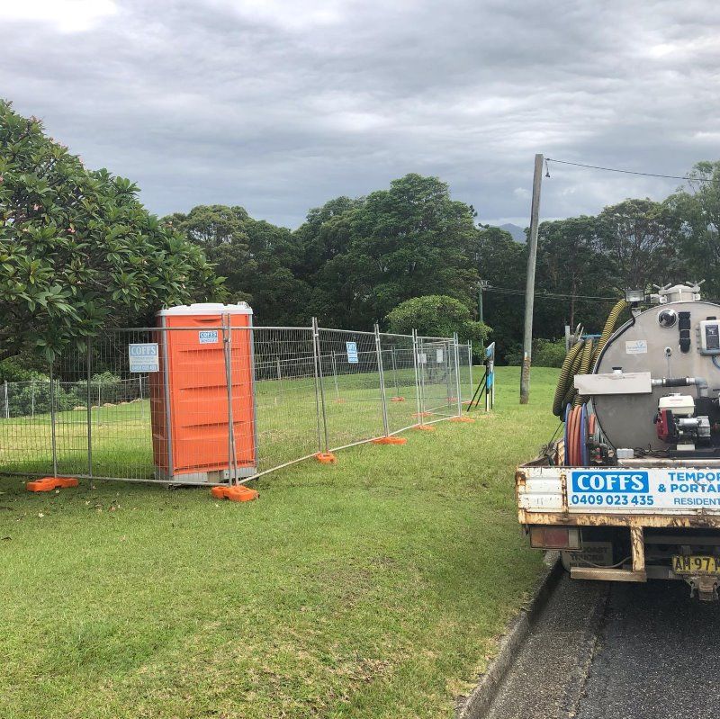 A Truck Is Parked On The Side Of The Road Next To A Portable Toilet — Coffs Temporary Fencing Pty Ltd In Bellingen, NSW