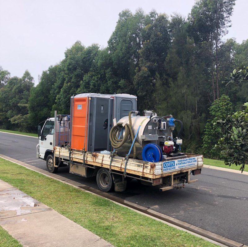 A Truck Is Parked On The Side Of The Road With Portable Toilets On The Back — Coffs Temporary Fencing Pty Ltd In Dorrigo, NSW