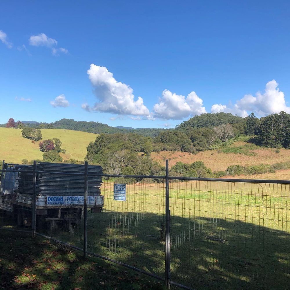A Truck Is Parked In A Field Behind A Fence — Coffs Temporary Fencing Pty Ltd In Moonee Beach, NSW