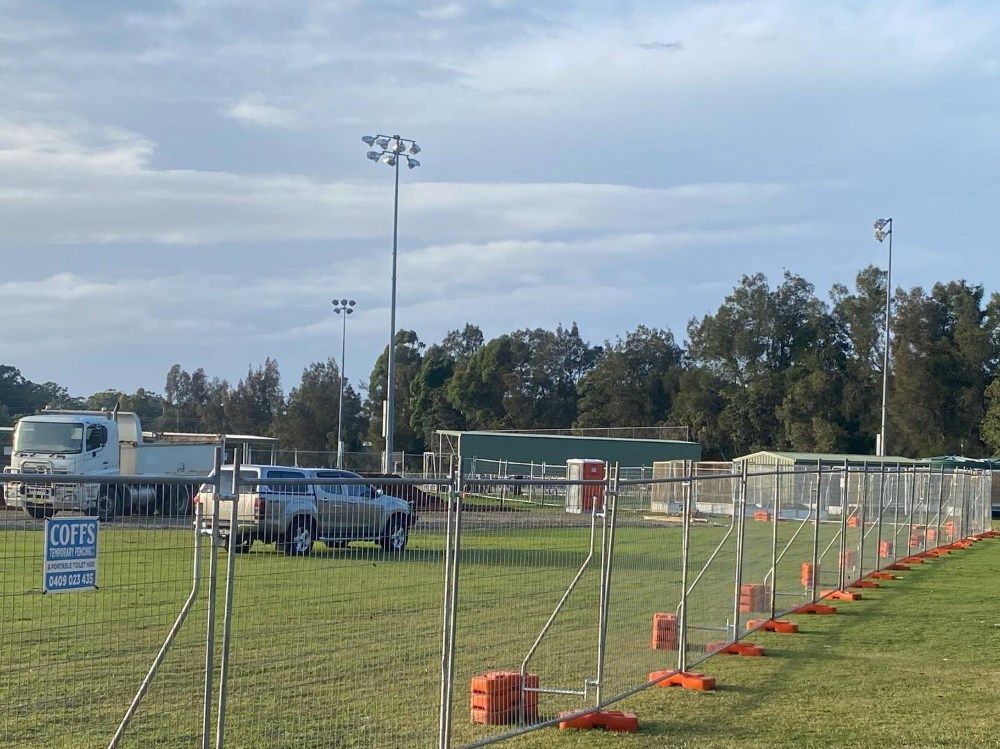 A White Truck Is Parked In A Grassy Field Behind A Fence — Coffs Temporary Fencing Pty Ltd In Grafton, NSW