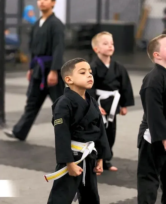 A group of young boys are practicing martial arts in a gym.