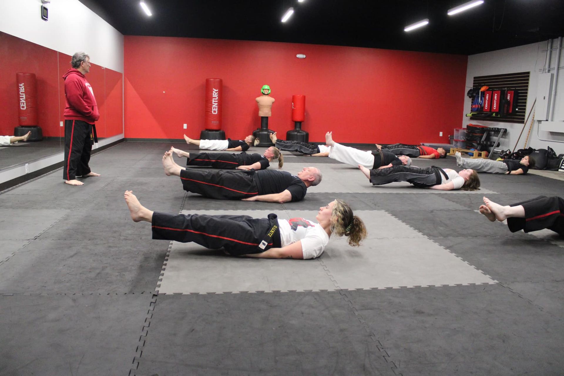 A group of people are laying on the floor in a gym.