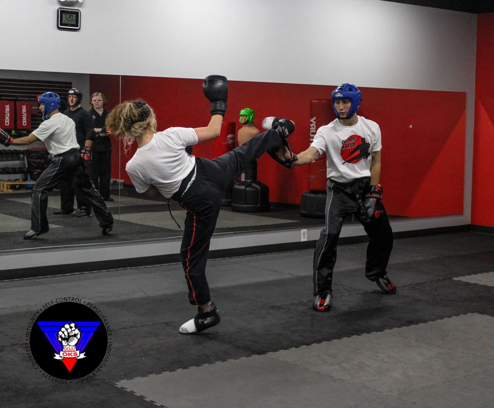 A woman is kicking a man in a gym