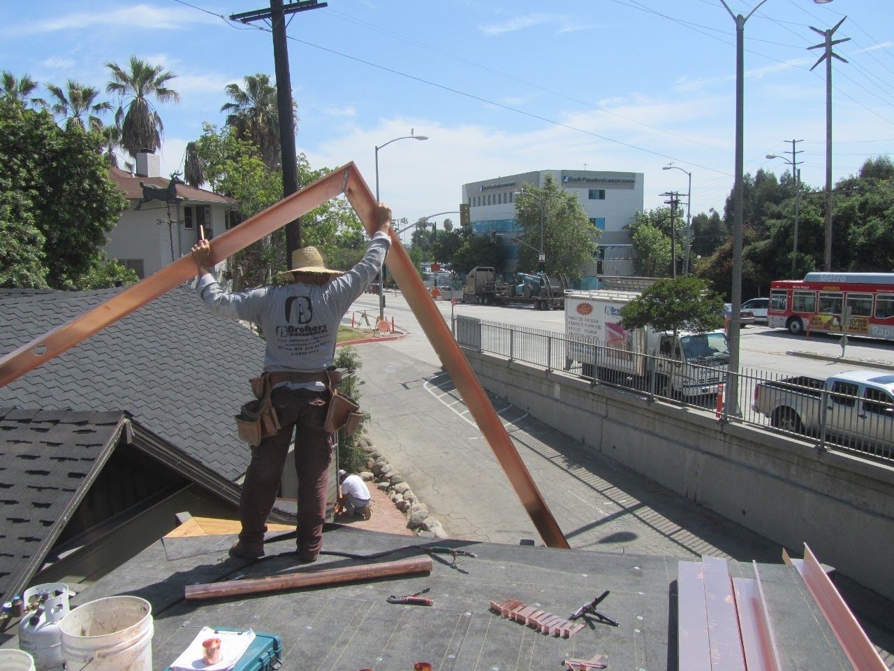 Roofer on a rooftop installing copper flashing. Sunny day, city backdrop.