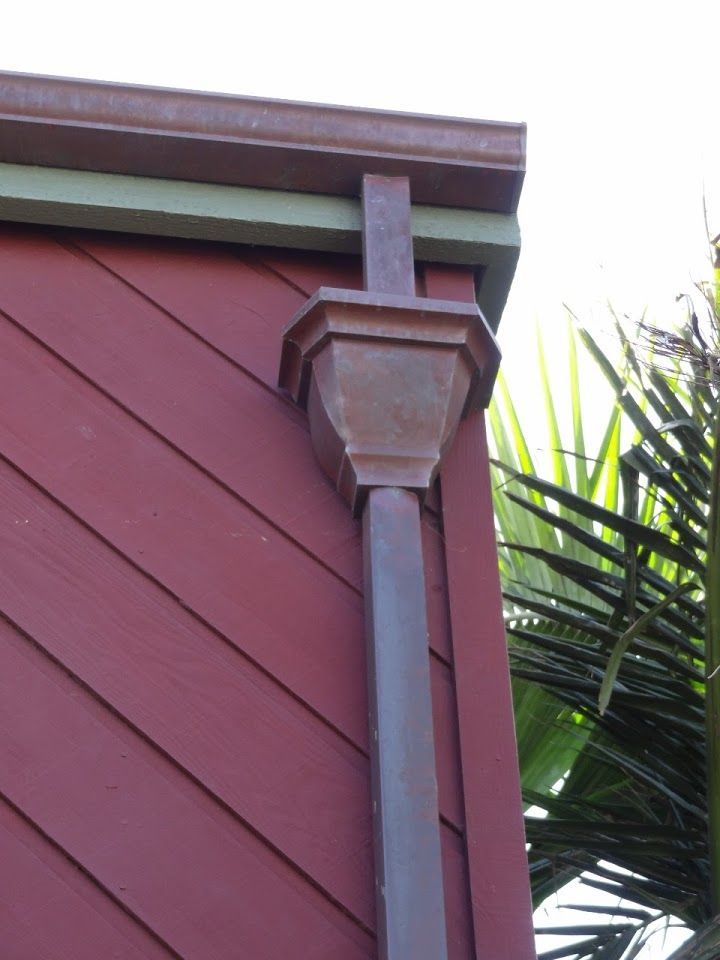Red building corner with copper gutter and downspout. Green trim.