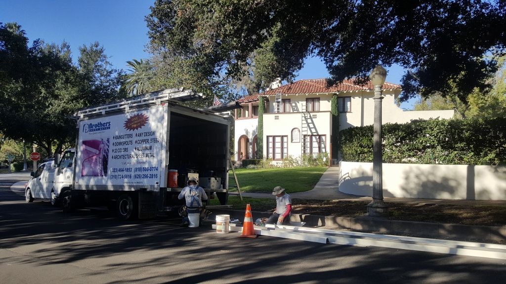 A truck with painters in front of a house on a sunny day.