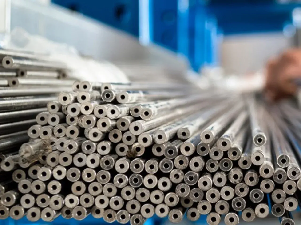 A bunch of metal pipes are stacked on top of each other in a warehouse.