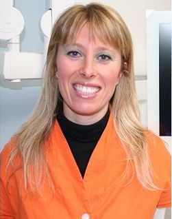Donna sorridente con una camicetta arancione sullo sfondo chiaro di un ufficio.