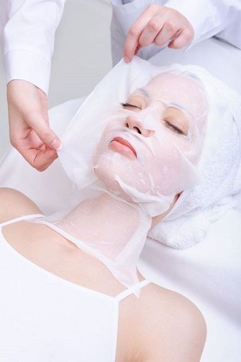 Trattamento viso in spa con una donna che riceve una maschera in tessuto mentre è sdraiata