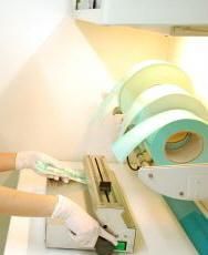 Mani guantate intente a caricare materiali in uno sterilizzatore o in una macchina confezionatrice