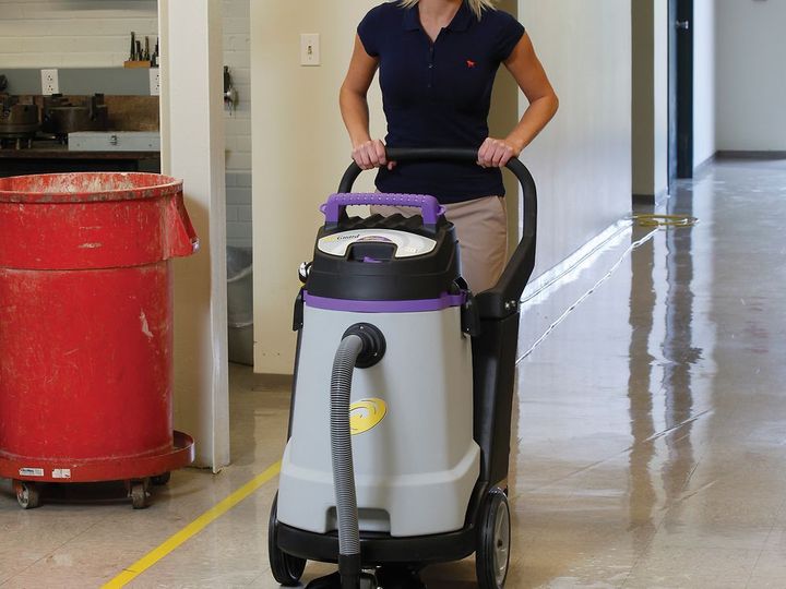 A group of cleaners are cleaning an office with a vacuum cleaner.